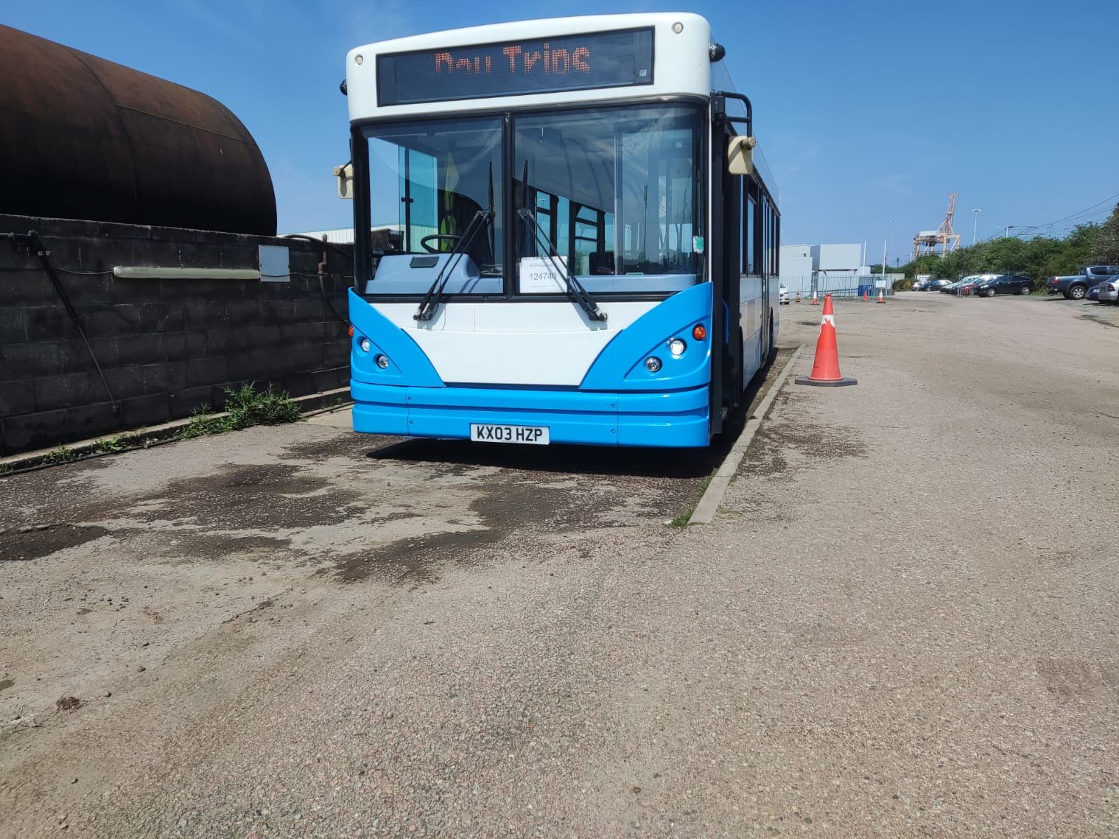 Front of a blue and white bus with a Day Trips destination display, parked on a hard standing